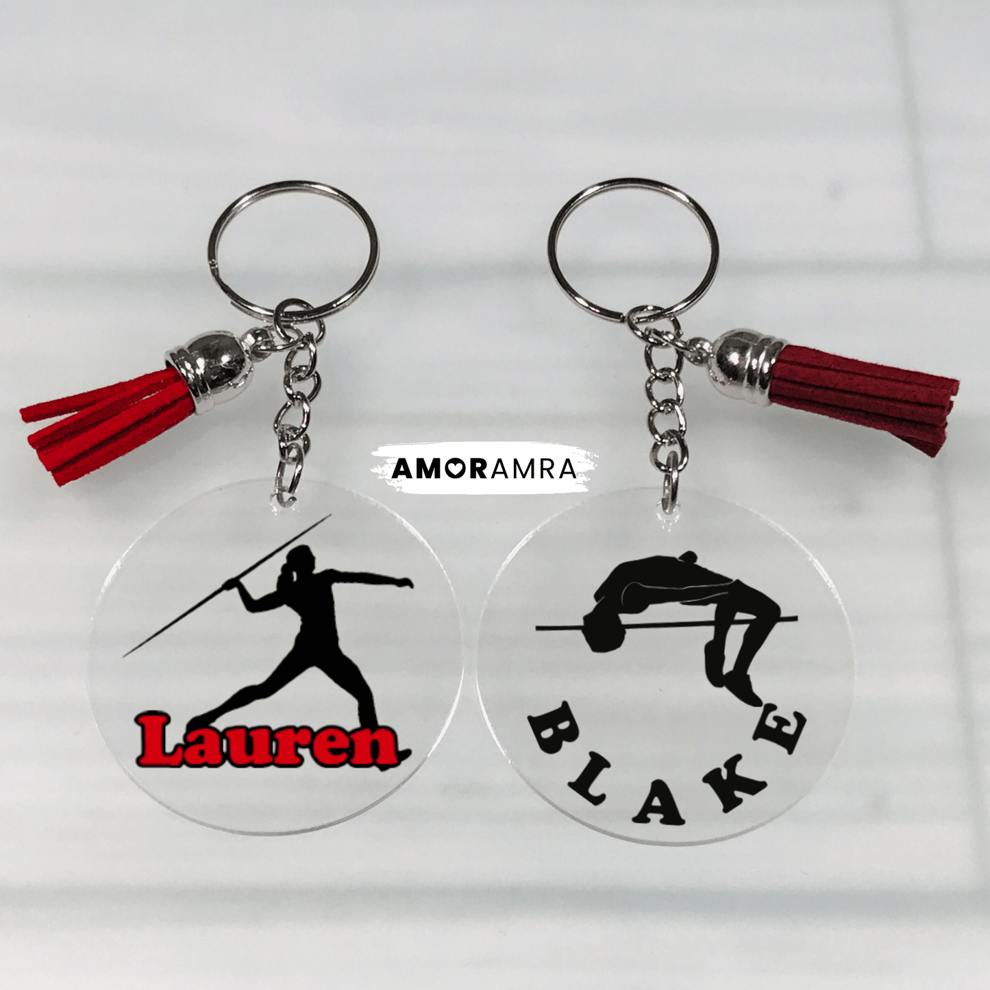 Two keychains with silhouettes of a javelin thrower and a pole vaulter, each labeled with a name, on a white background.