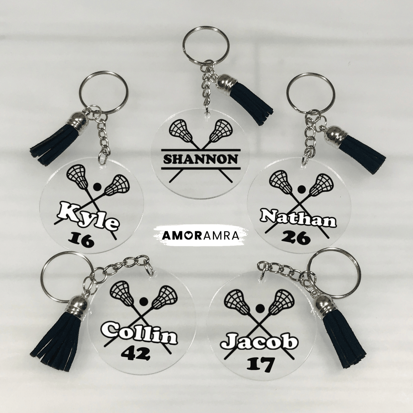Set of personalized lacrosse keychains with names and numbers on a white background. May include: personalized lacrosse keychain designs featuring clear acrylic circles with black lacrosse sticks and player names. Each keychain includes a black tassel. These custom sports keychains are ideal for lacrosse players or fans. Personalized Lacrosse Keychain, Lacrosse Team Gift, Lacrosse Bag Tag, Lacrosse Gear Tag, Lacrosse Gift, LAX Bag Tag, Lacrosse Coach Gift