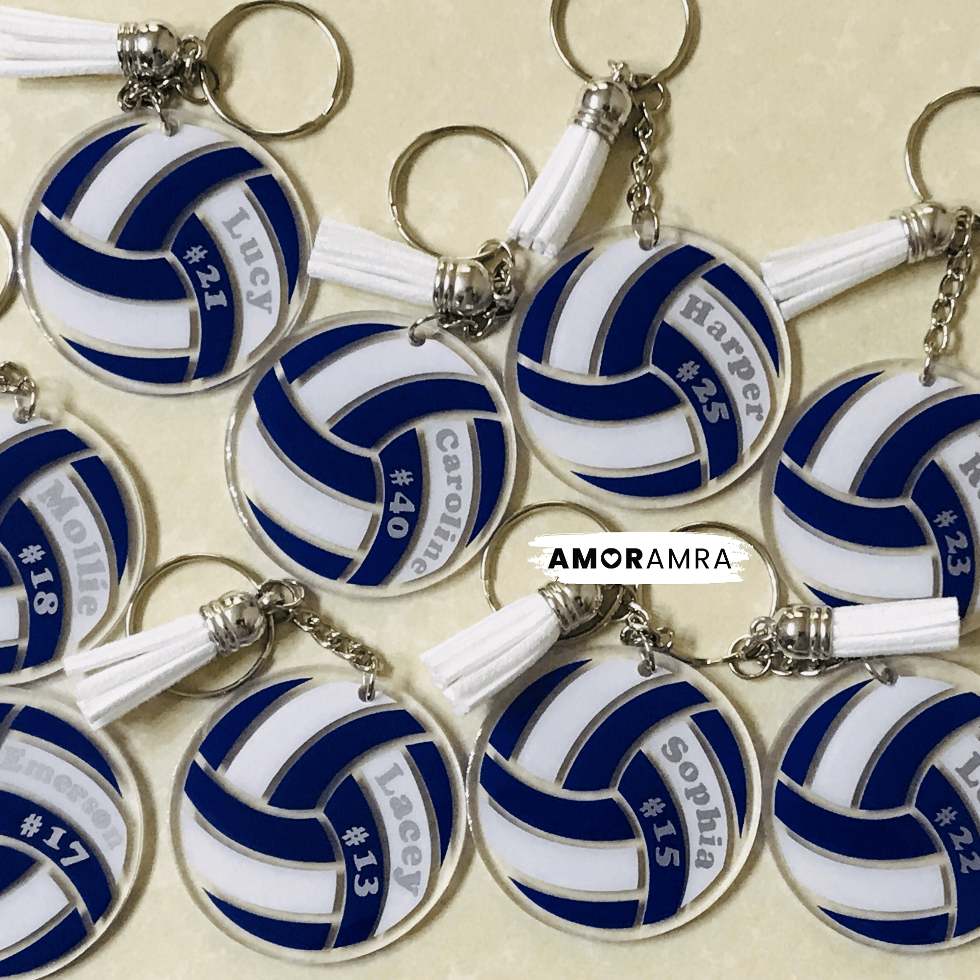 Volleyball keychains with personalized names on a beige background, featuring the brand 'AMORAMRA'.