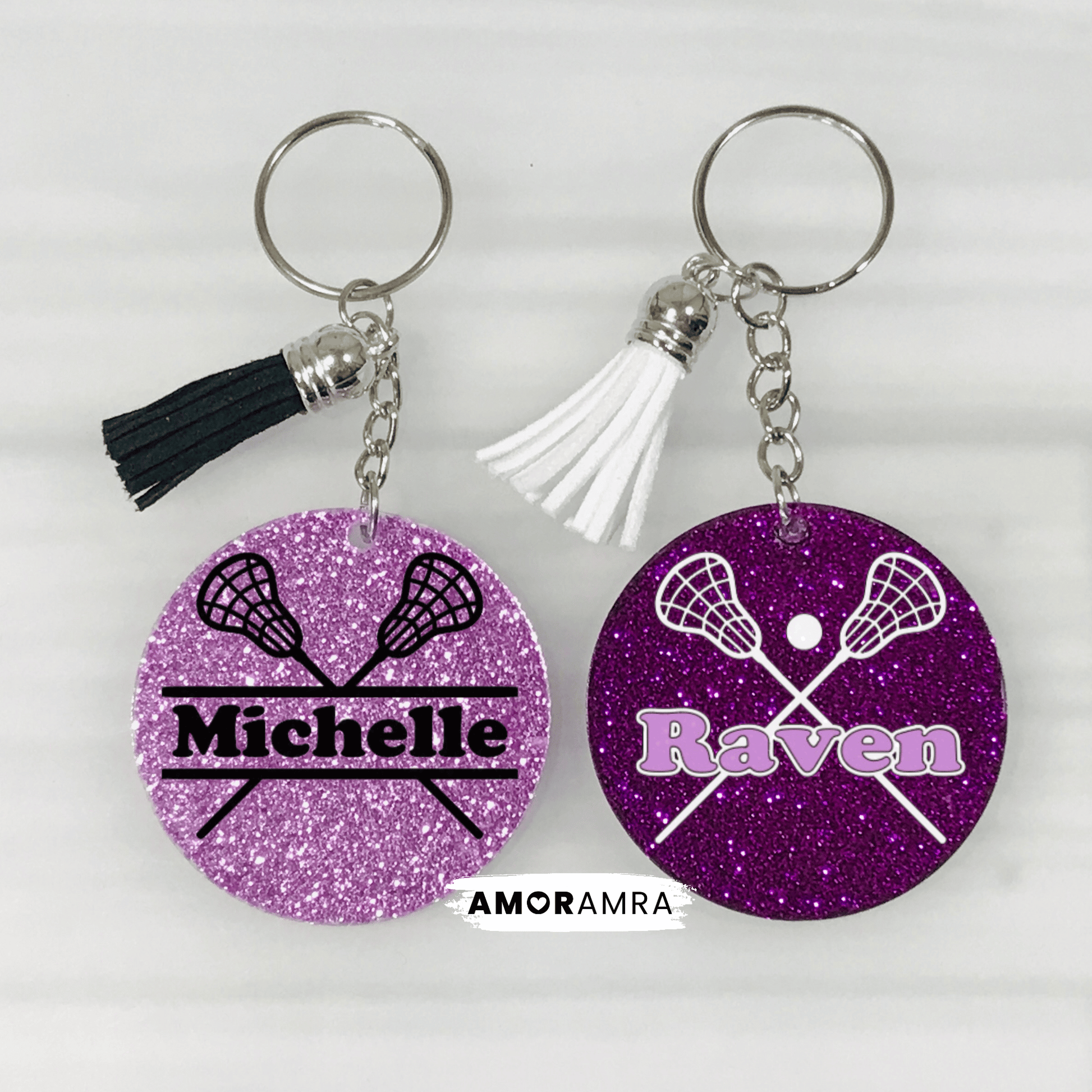 Two purple glitter keychains with lacrosse designs and names 'Michelle' and 'Raven'.