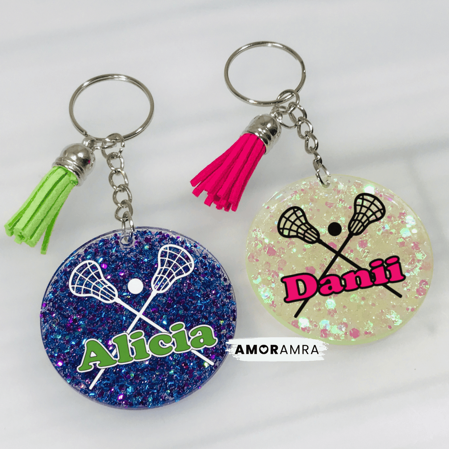 Two glittery keychains with lacrosse designs and personalized names on a white background.