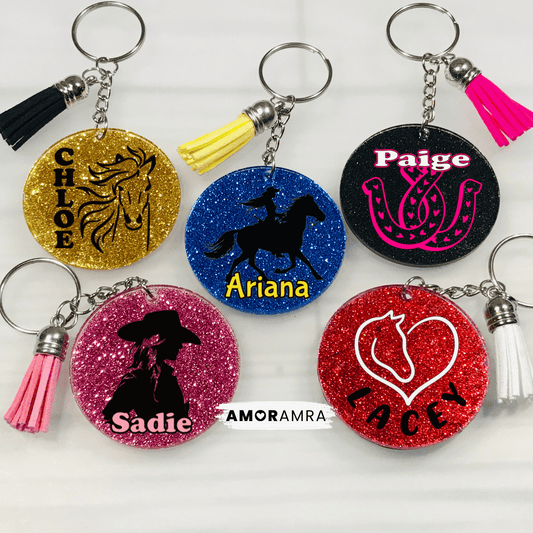 Personalized Glitter Horse Keychain. glitter horseshoe keychain. horse rider keychain. glitter round keychains with different horse themed designs and names. The gold keychain has a horse silhouette. The blue keychain has a silhouette of a person riding a horse. The black keychain has a horseshoe design. The pink keychain has a silhouette of a person wearing a cowboy hat. The red keychain has a heart with a horse silhouette inside. Personalized Horse Keychain, Horse Lover, Equestrian Keychain, Horse loss 