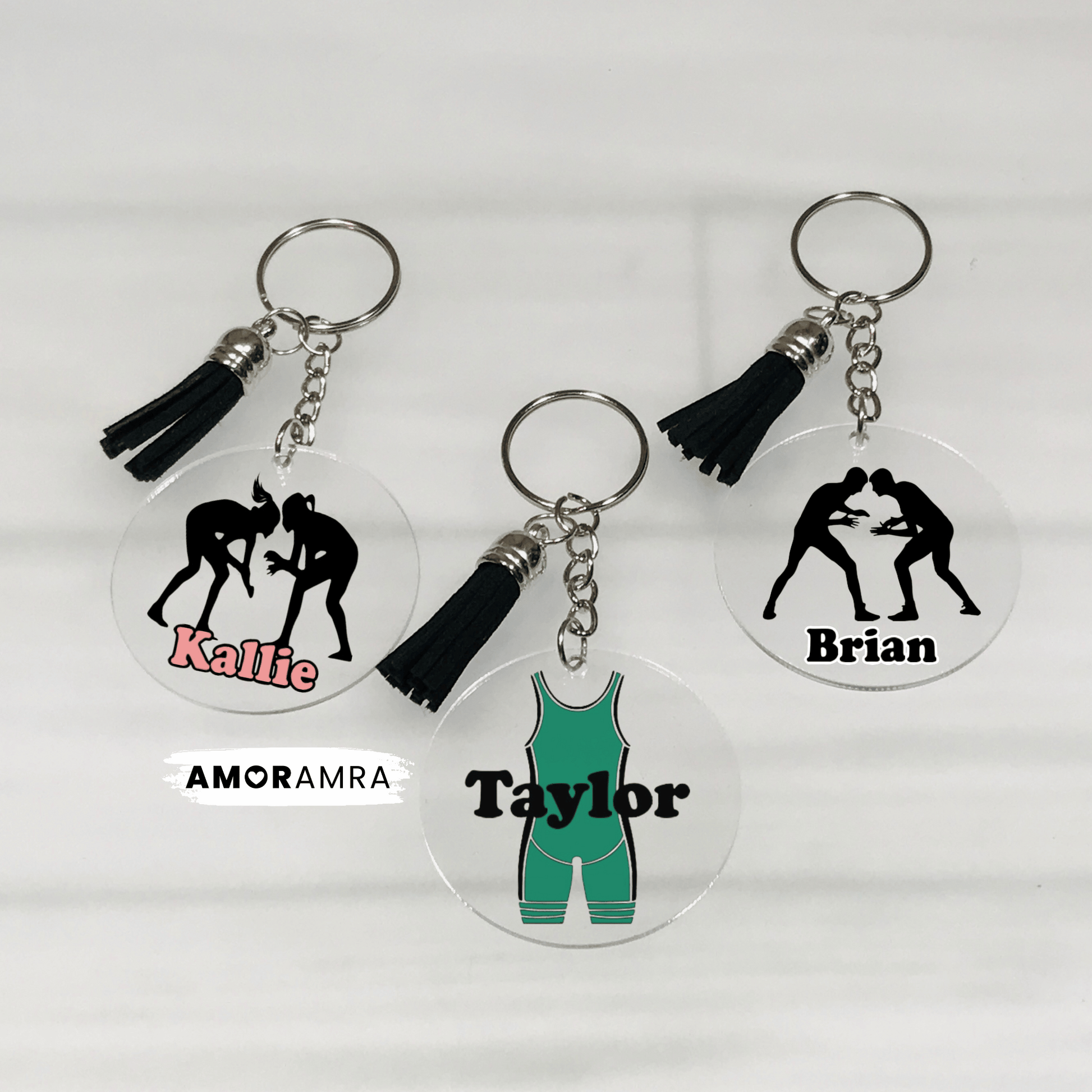 Three keychains with wrestling-themed designs and names on a white background